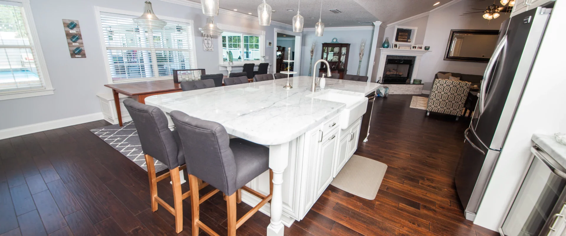 white kitchen with a platinum fridge a marbled countertop with grey wood chairs ponte vedra beach fl